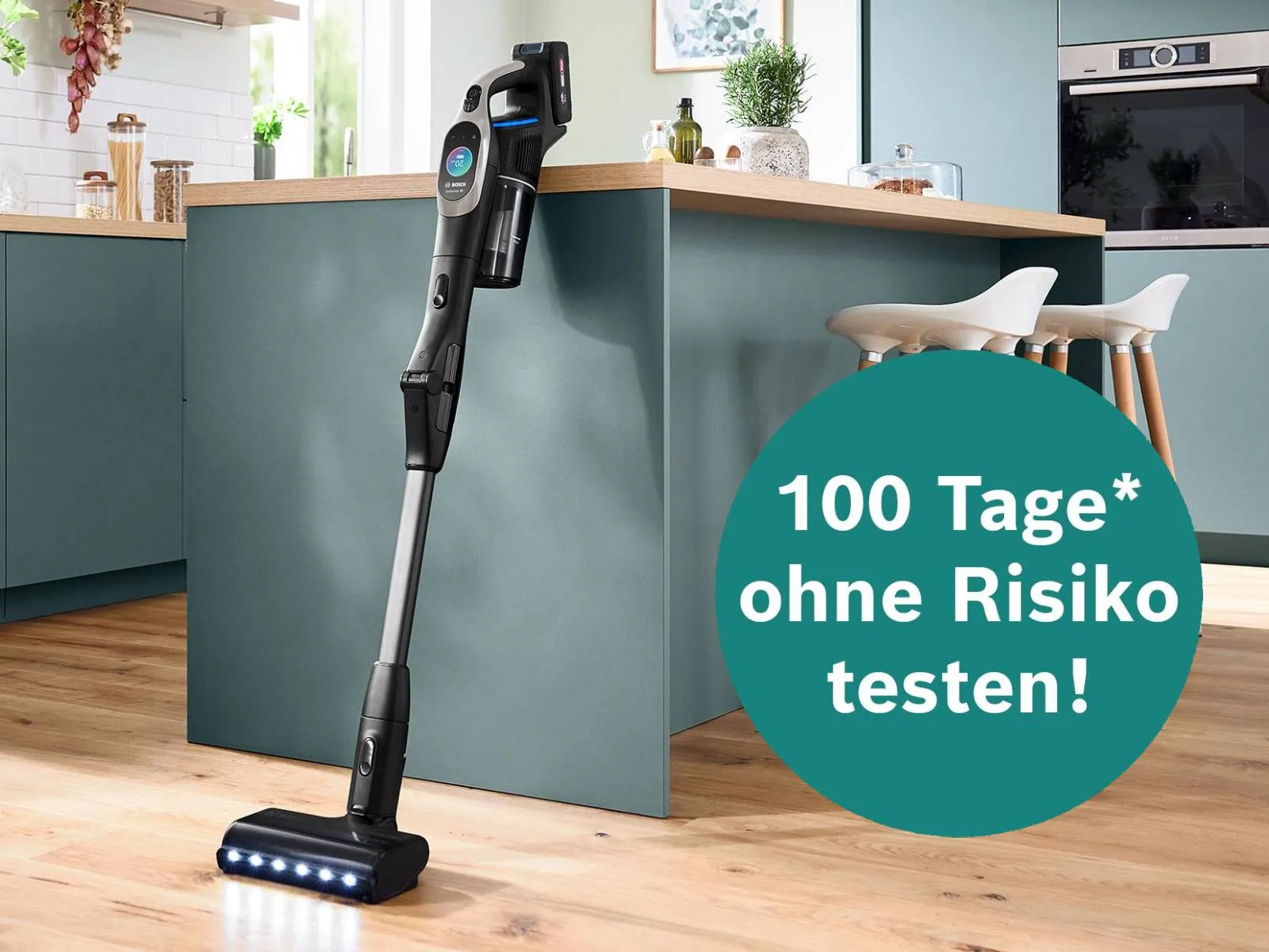 Moderne Küche mit grünen Schränken, Holzarbeitsplatte und einem kabellosen Staubsauger.
