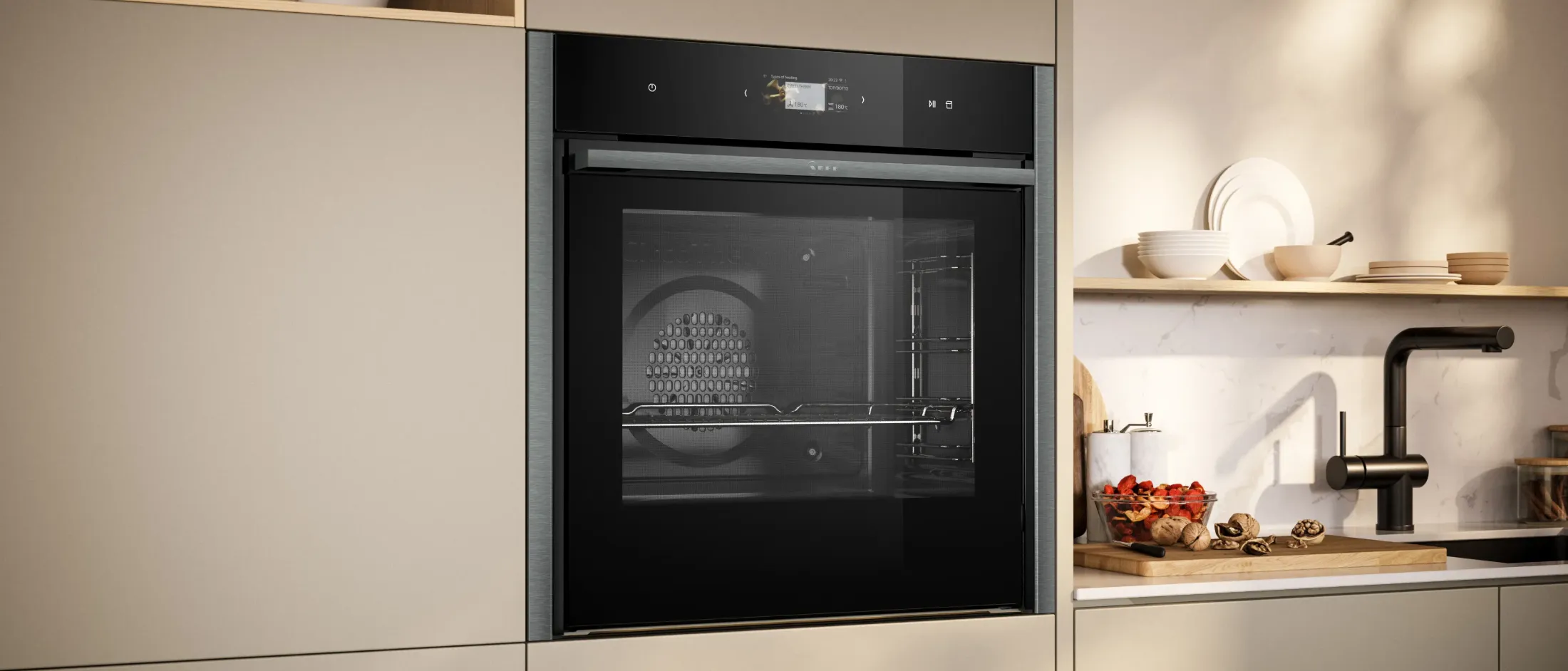Modern built-in black oven in a beige kitchen with a wooden shelf, white dishes, black faucet, and a counter with dried fruits and nuts.