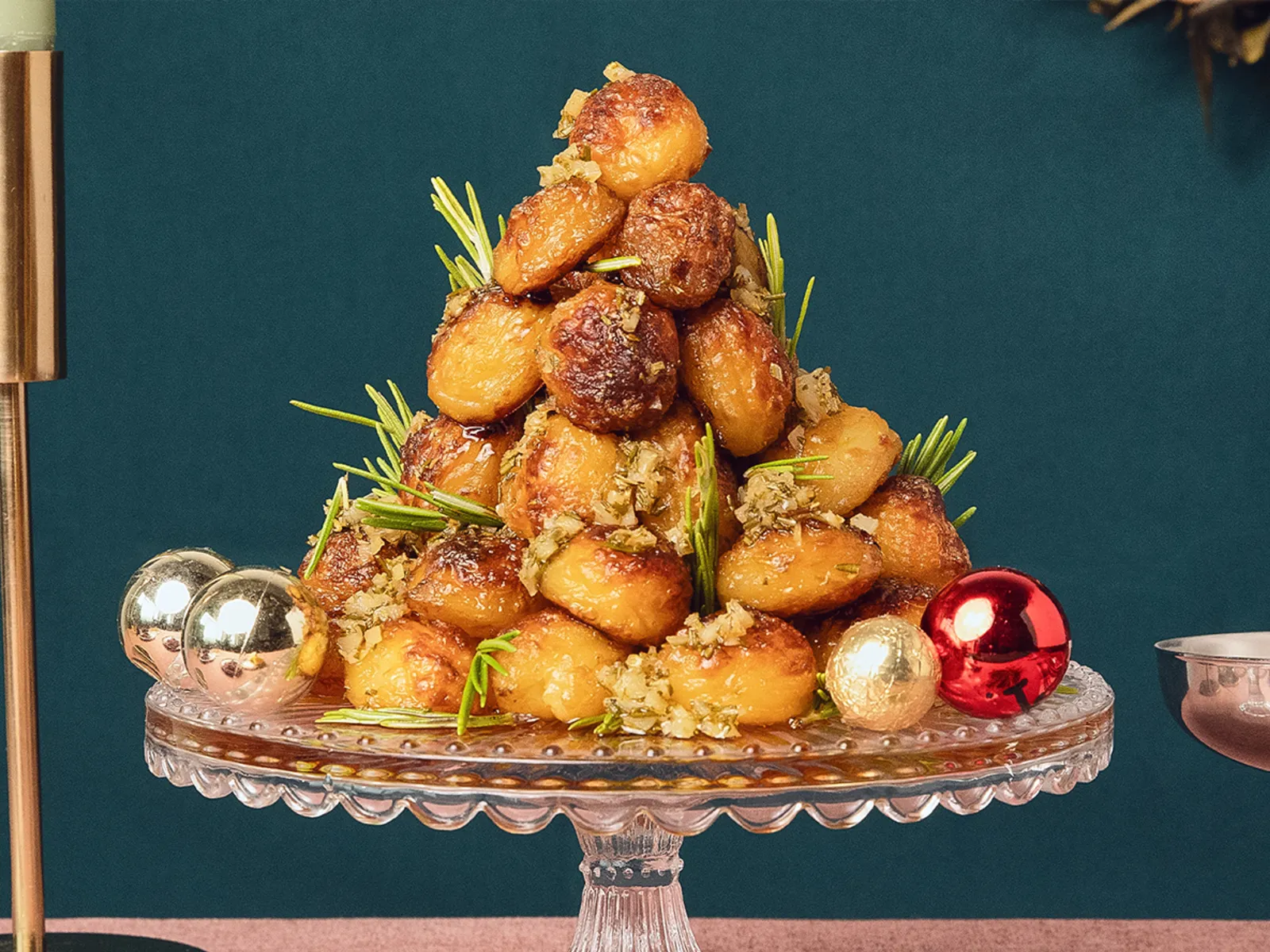 Golden crispy roast potatoes arranged in a cone shape on a cake stand in a modern Christmas setting.