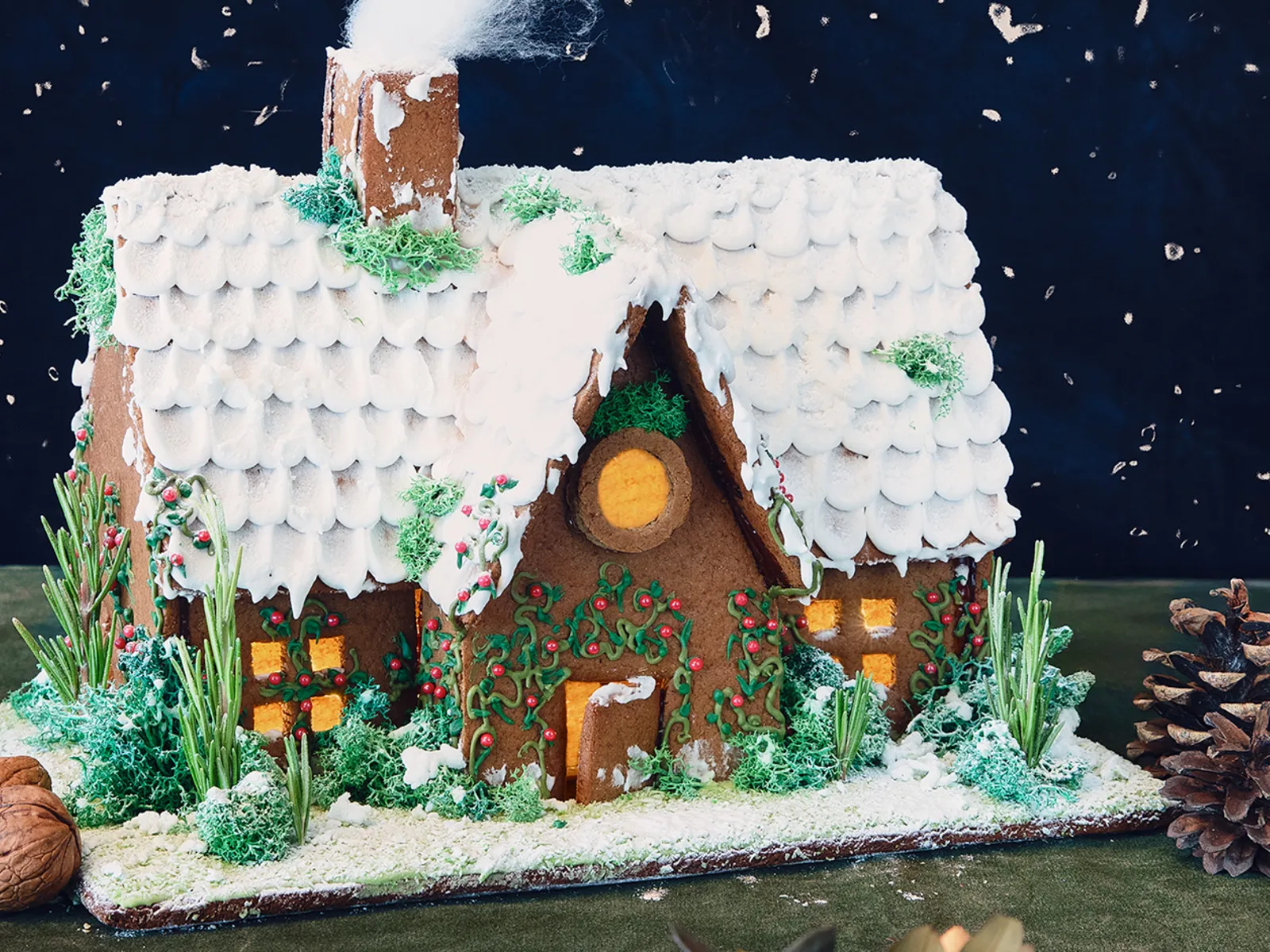 Festive Christmas gingerbread house decorated with icing and festive sprinkles.