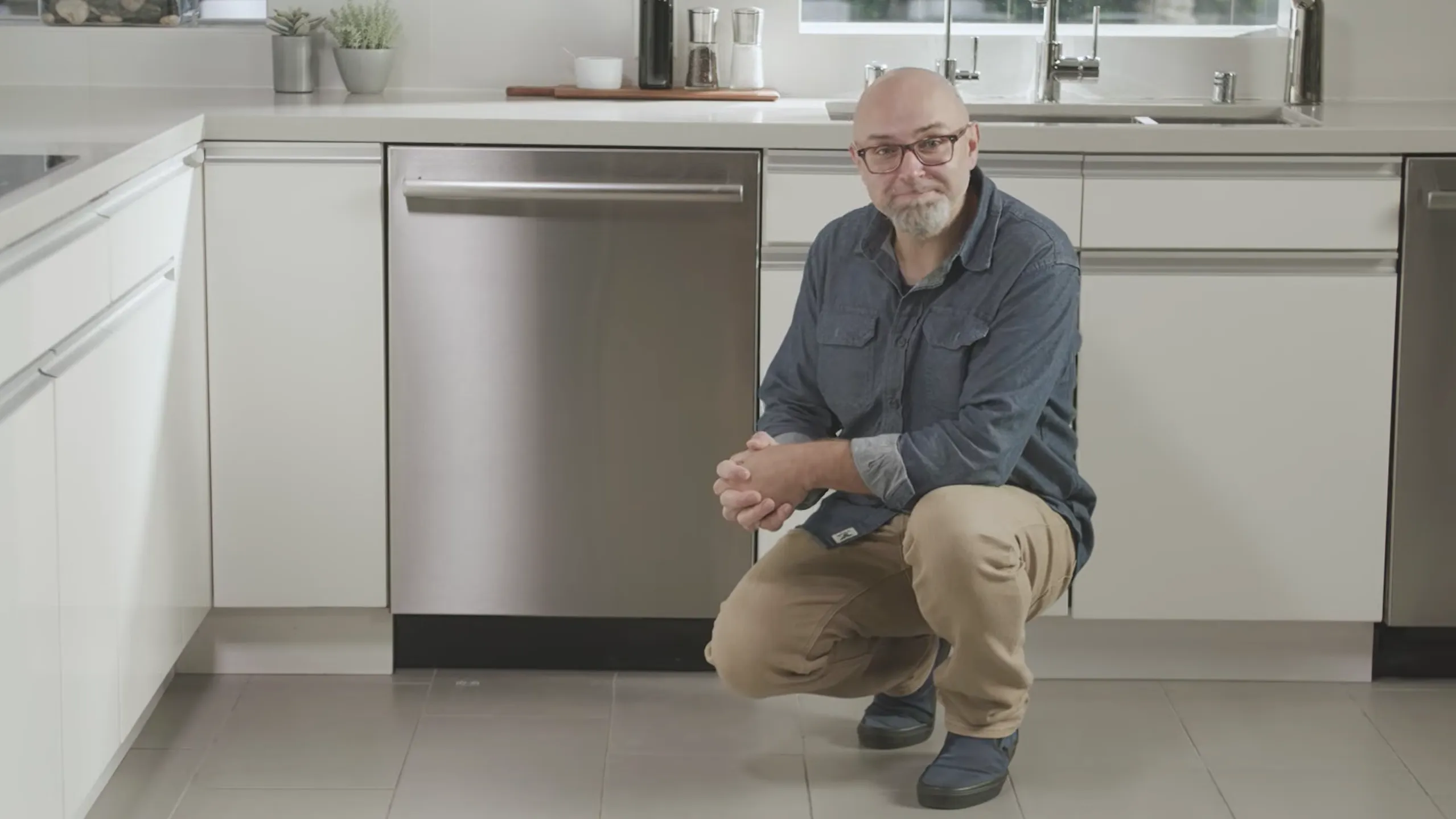 man crouching in front of dishwasher inside kitchen