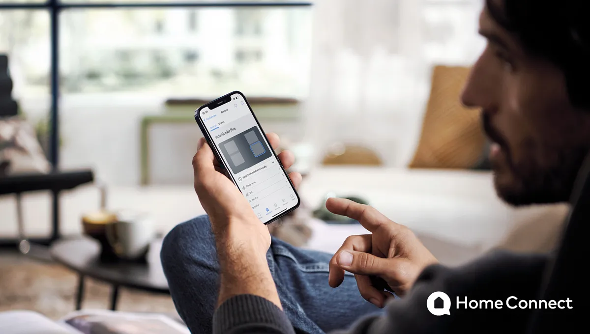 De man gebruikt smartphone app op de bank in de woonkamer.