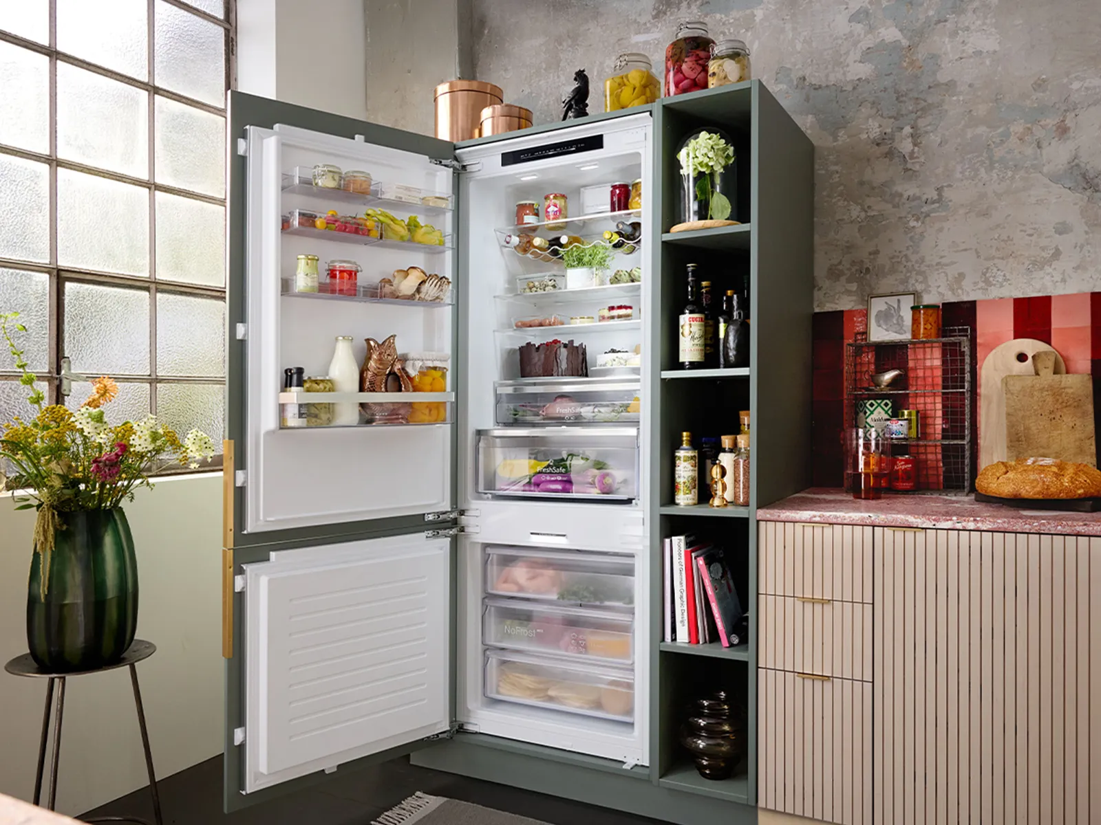 A modern kitchen featuring a stylish refrigerator filled with various foods.