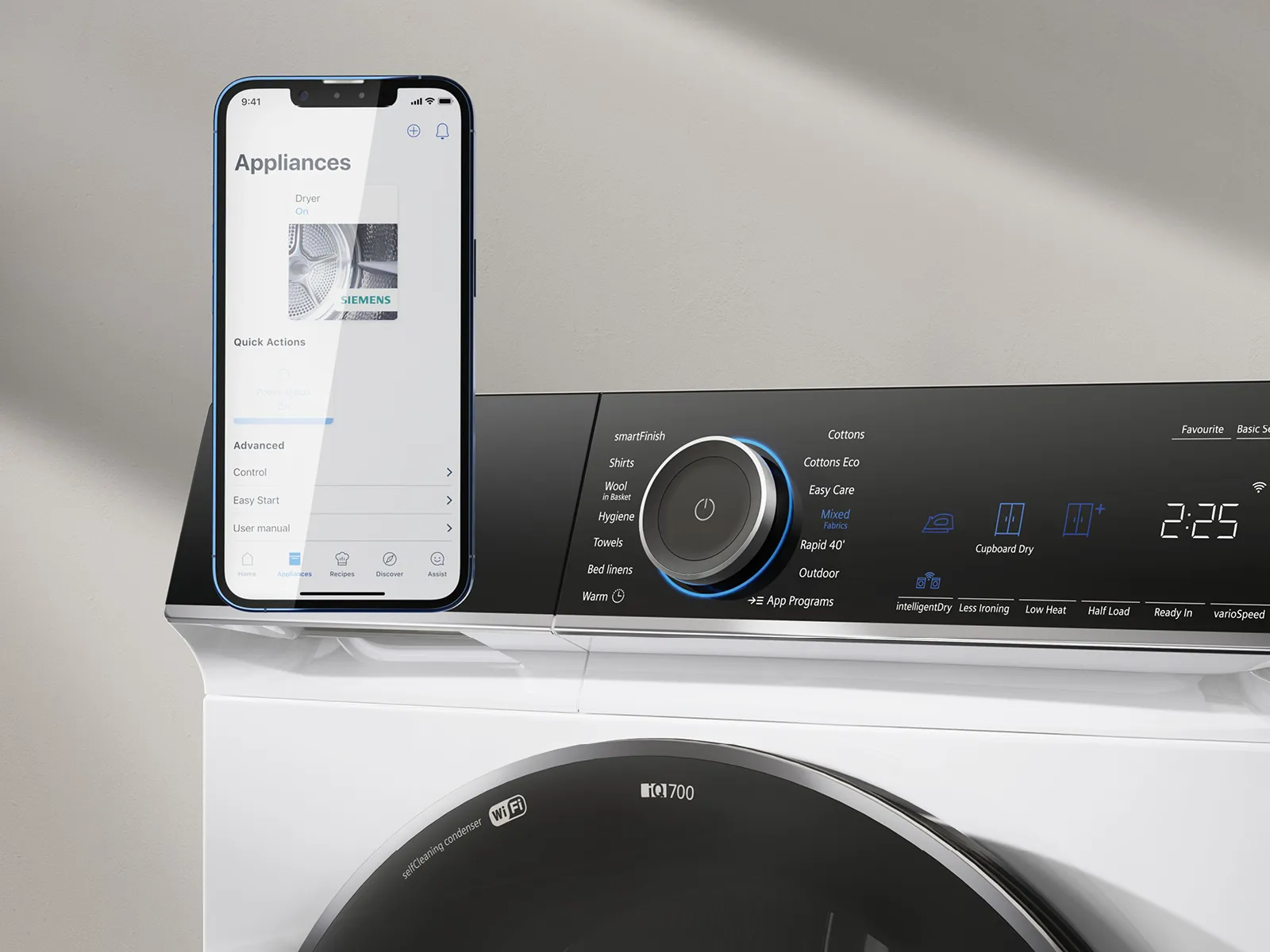 Smartphone connecté aux appareils ménagers intelligents, machine à laver et panneau de commande numérique.