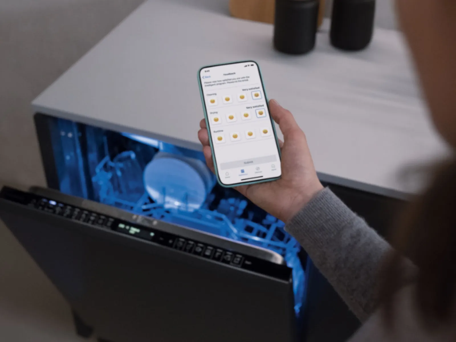 Personne tenant smartphone, ordinateur portable avec éclairage bleu, décoration en bois sur table.