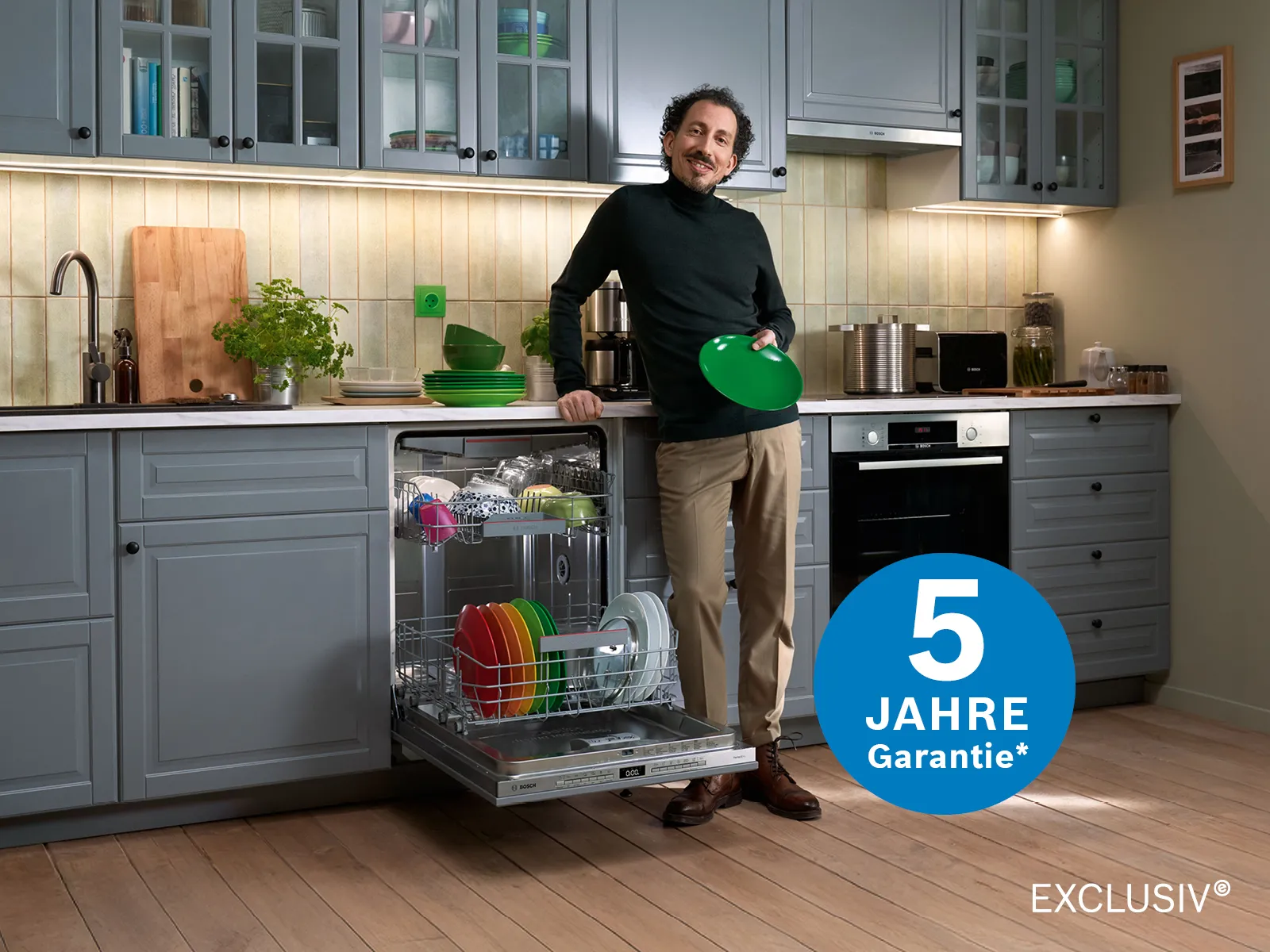 Ein Mann steht mit Tellern in der Hand vor einer geöffneten Bosch Spülmaschine.