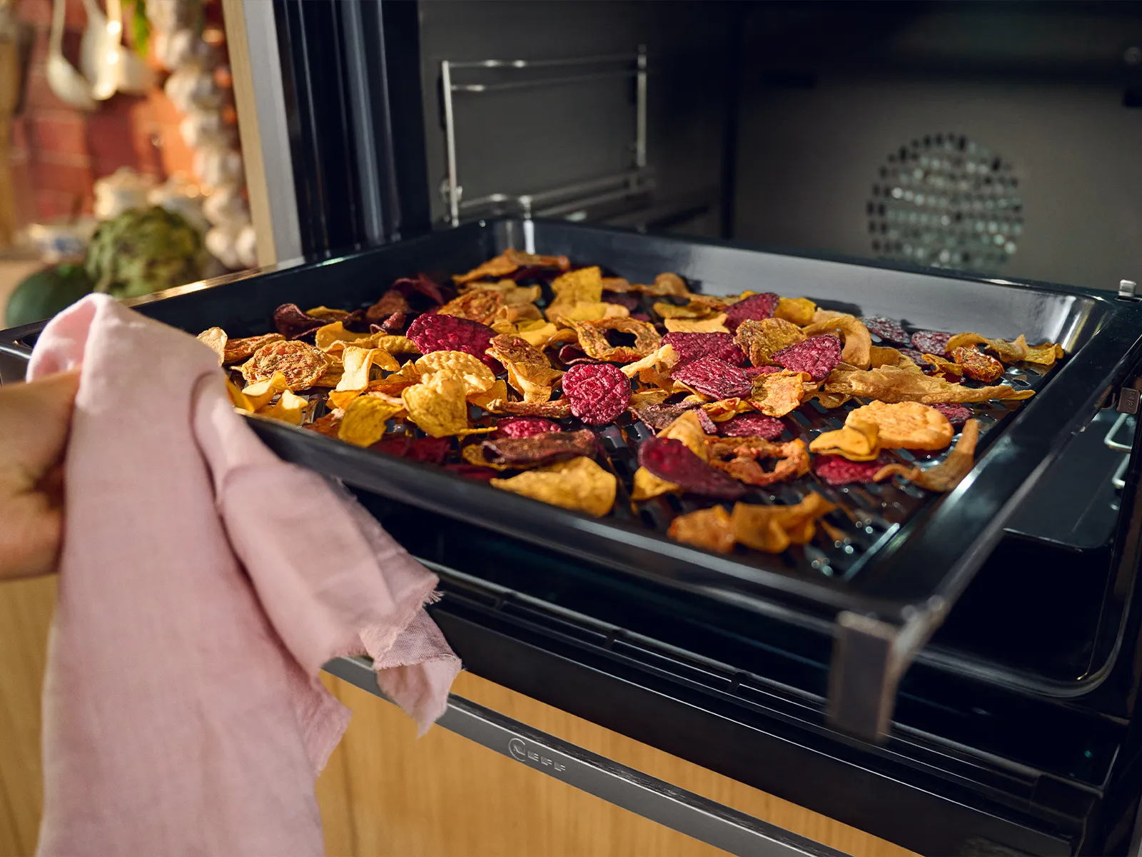 Baked root vegetables, including carrots, beets, and potatoes, arranged on a baking sheet in the oven.