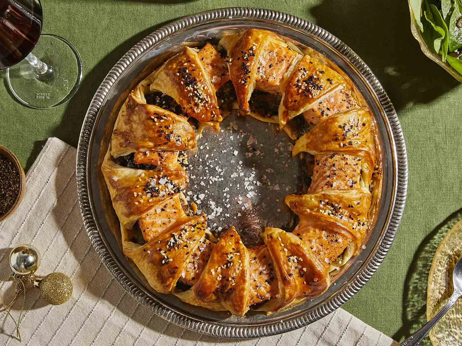 Circular pastry dish with caramelized topping, surrounded by spices, herbs, and a wine glass.