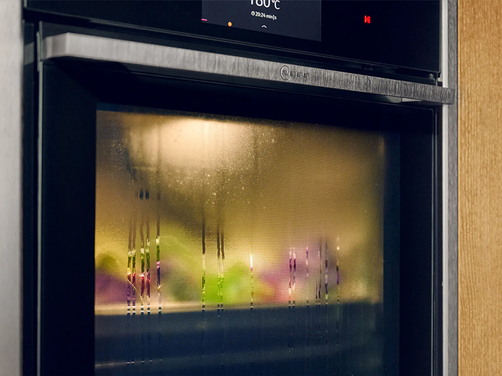 Una mano estrae un vassoio per cottura a vapore da un forno nero elegante, mostrando la tecnologia moderna in cucina.