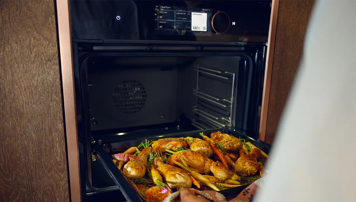 Teglia piena di pollo arrosto inserita in un forno con profili laterali Brushed Bronze