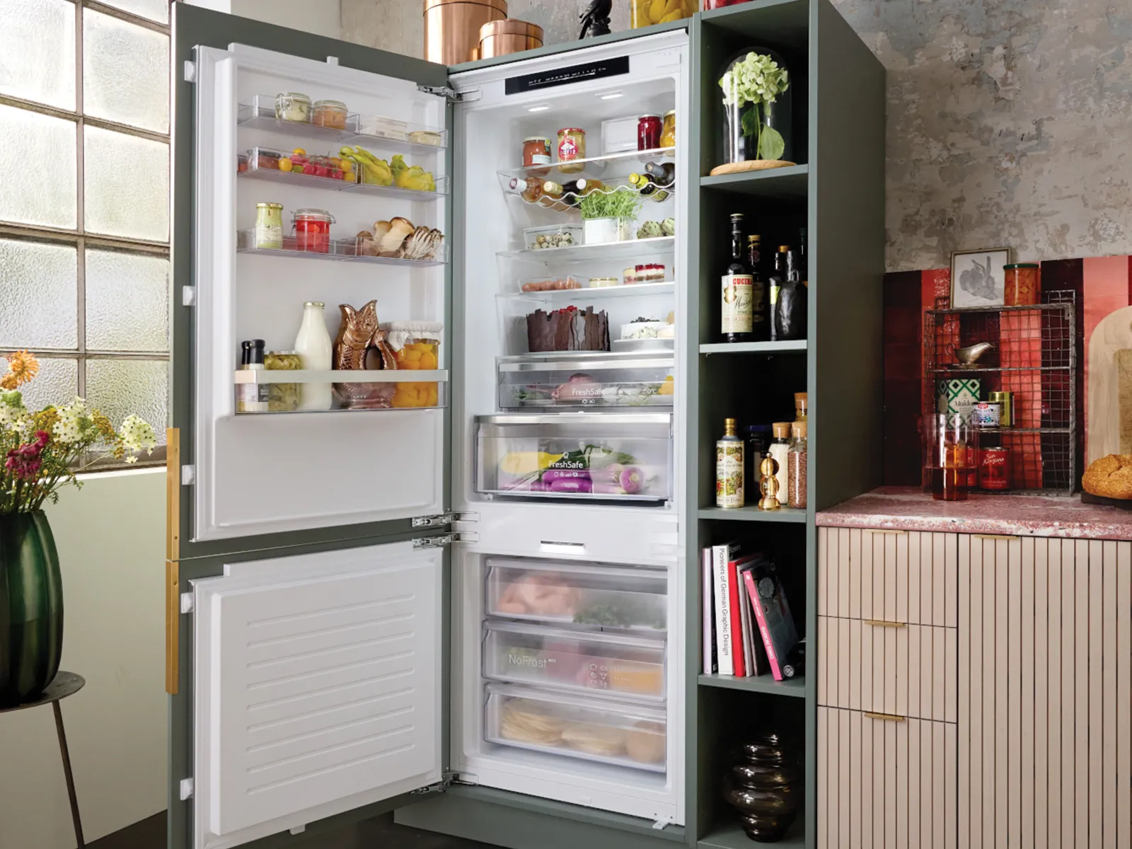Ein geöffneter Kühlschrank in einer gemütlichen Küche mit frischen Zutaten im Inneren, Blumen auf einem Beistelltisch und einem frischen Laib Brot auf der Arbeitsplatte.