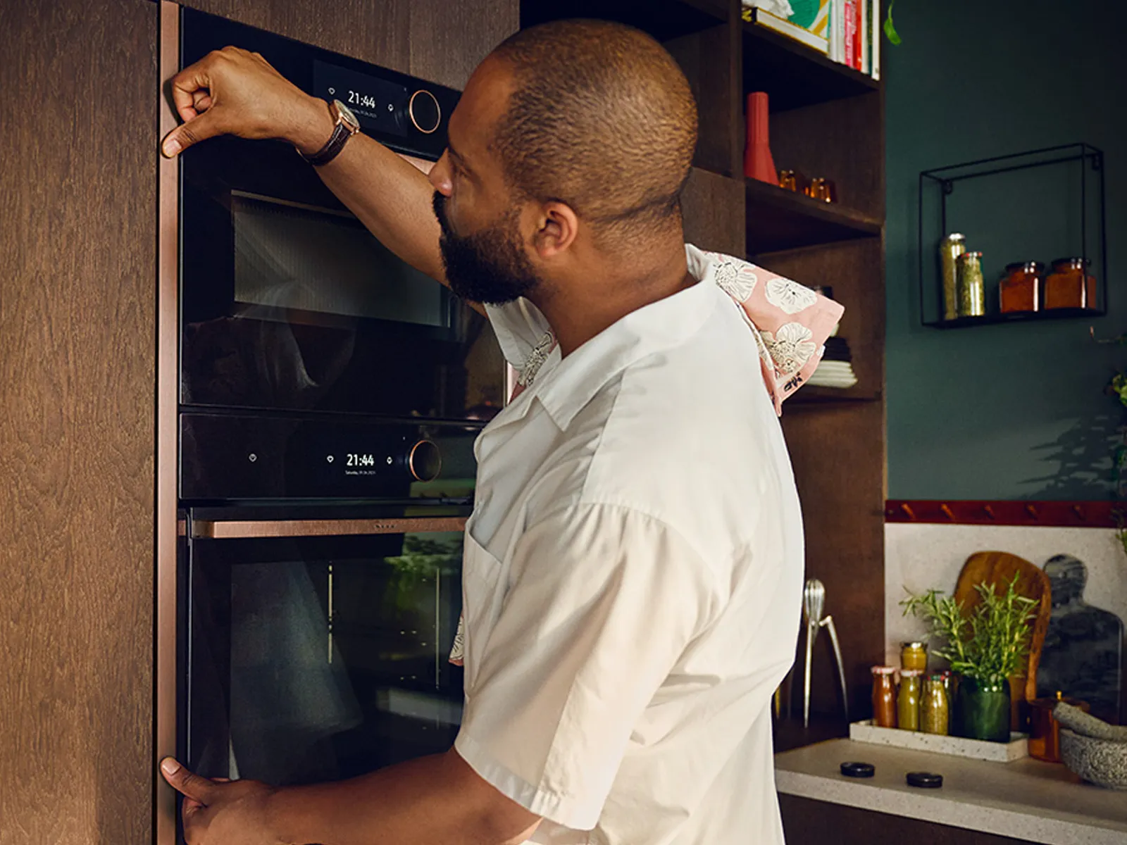 A man in a kitchen installing a decorative trim piece on a NEFF built-in oven, part of the Flex Design series.