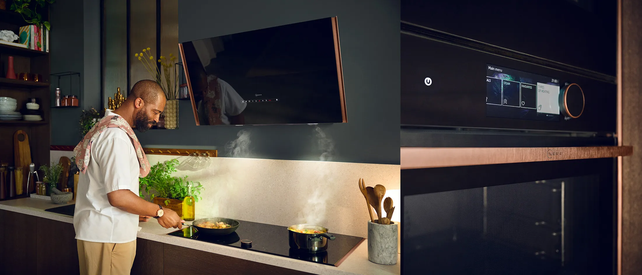 Man cooking in a modern kitchen, stirring vegetables in a steaming pan on the stove with herbs and utensils nearby.
