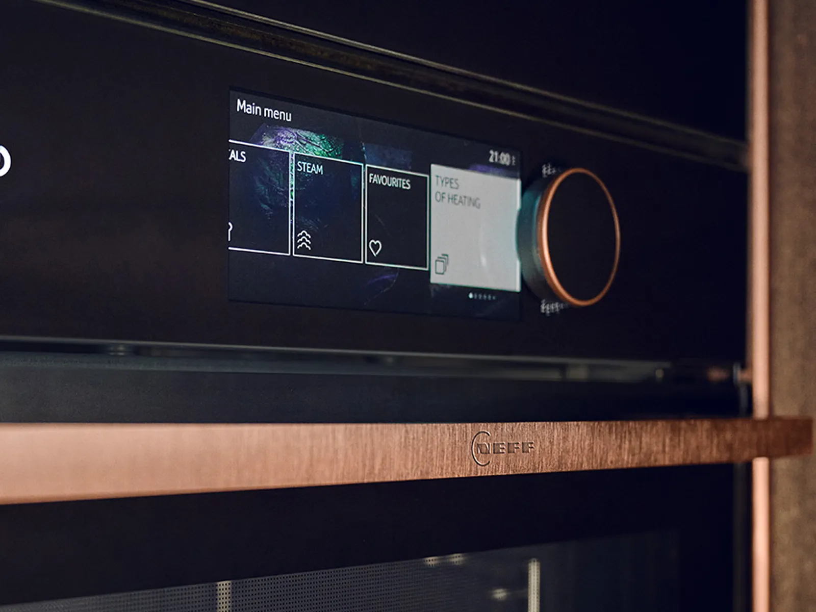 Close-up of a modern oven control panel with touchscreen display and a large rotary knob, showing heating options and temperature settings.