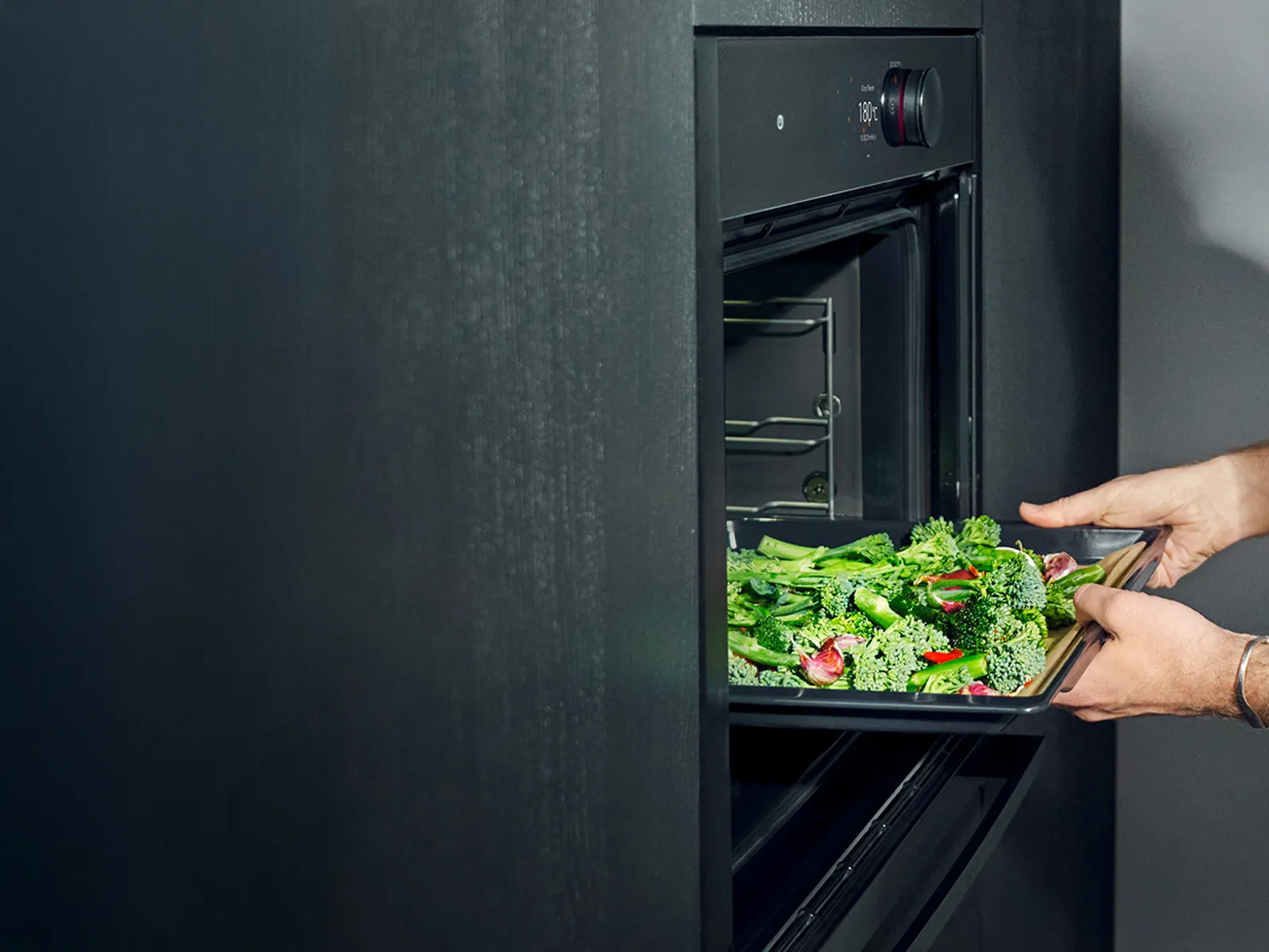 Open oven in Deep Black with tray of green vegetables 