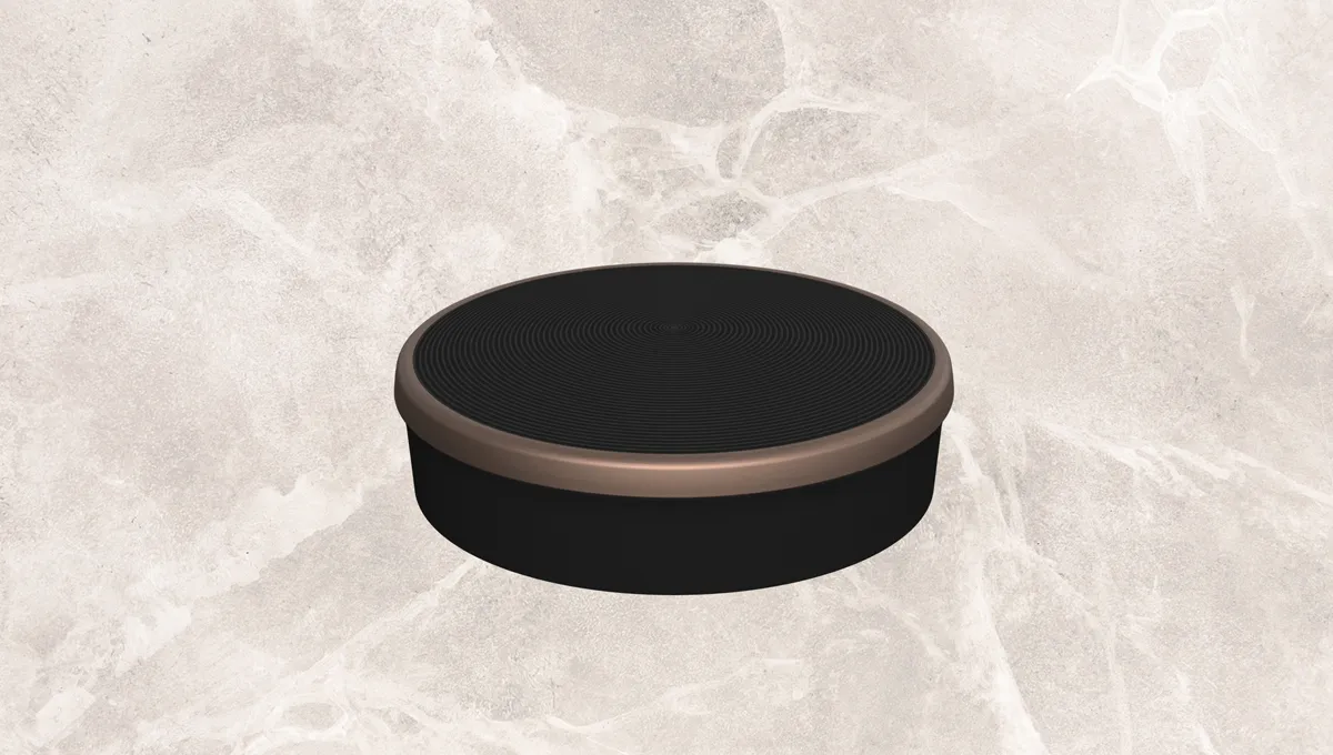 Black circular container with metallic rim on a marble background.