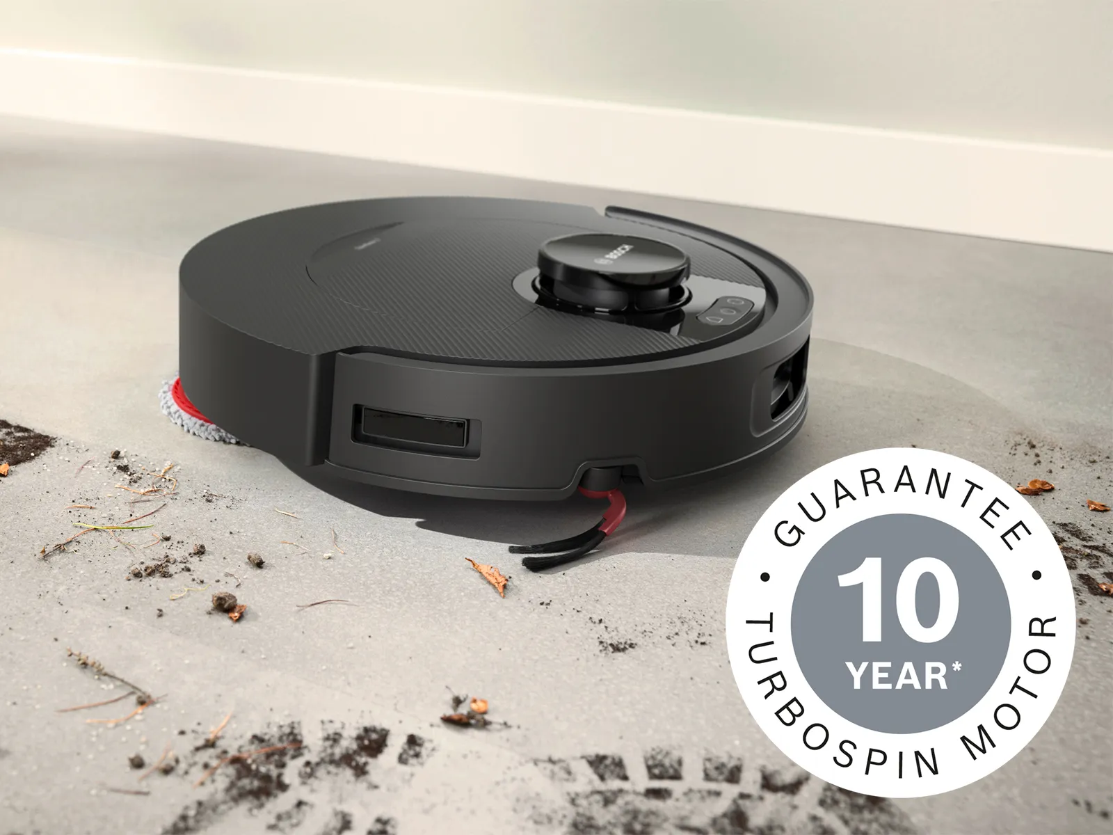 The Spotless 2 cleans a muddy floor, highlighting its German Quality Standards and 10-year motor guarantee.