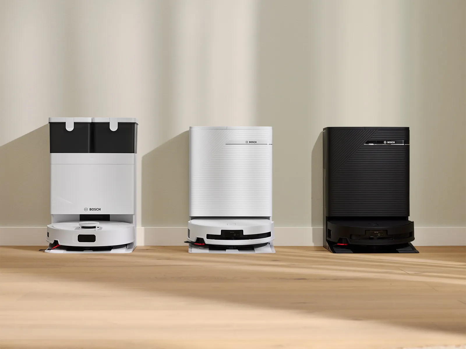 Three Bosch Spotless 2 vacuum & mopping robots displayed against a wall.