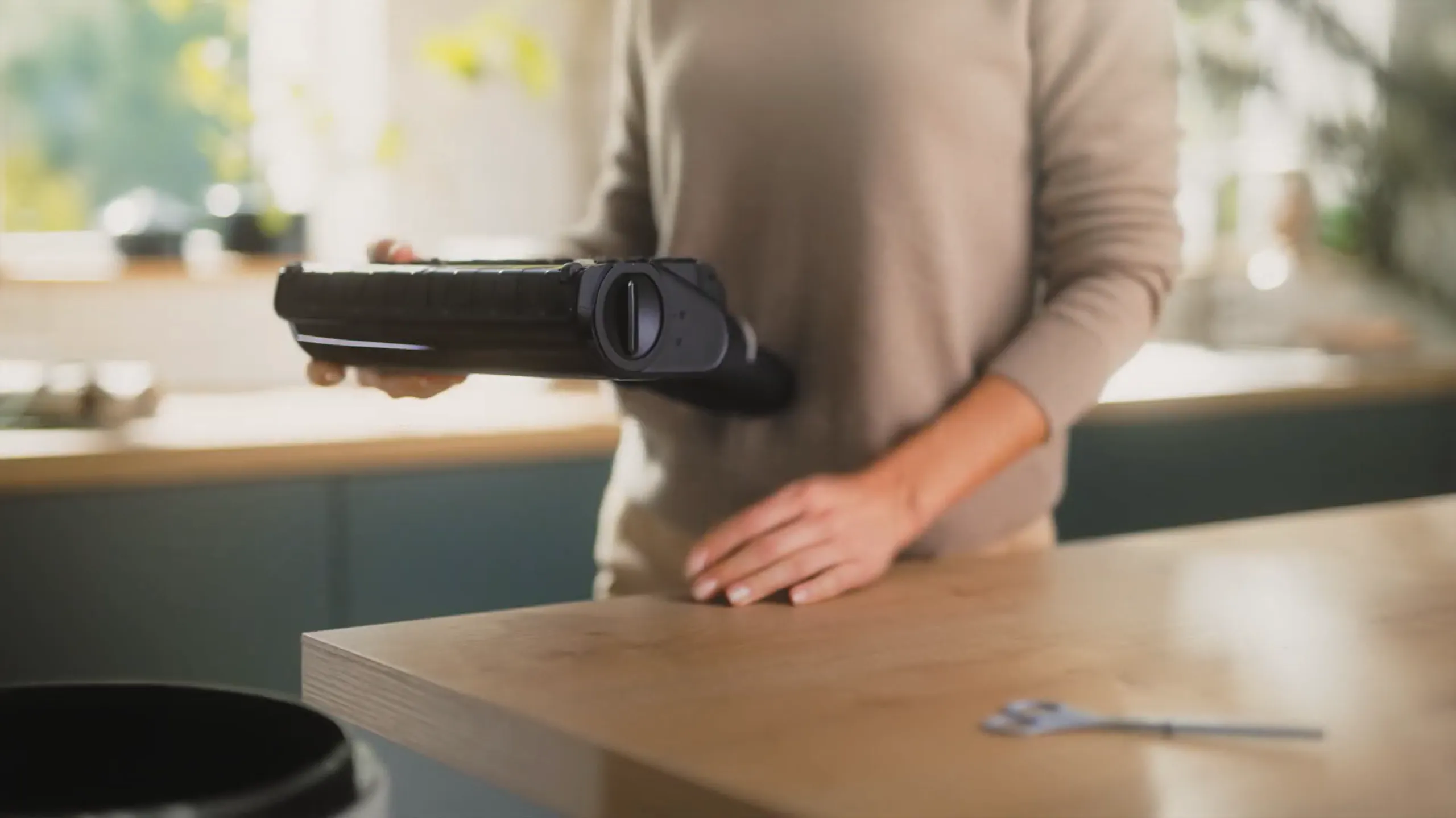 Person holding vacuum filter over trash inside a modern kitchen