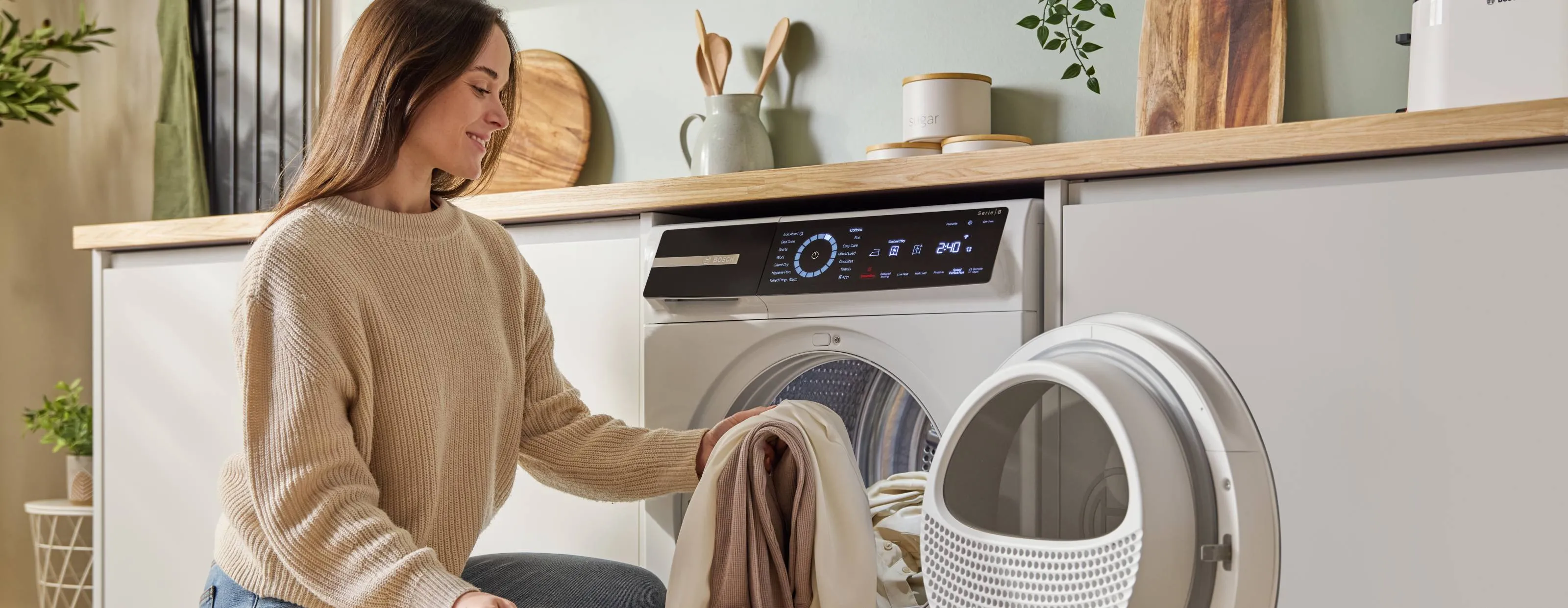 Bright, modern laundry room with white washing machine and dryer, shelving, and tiled floor.