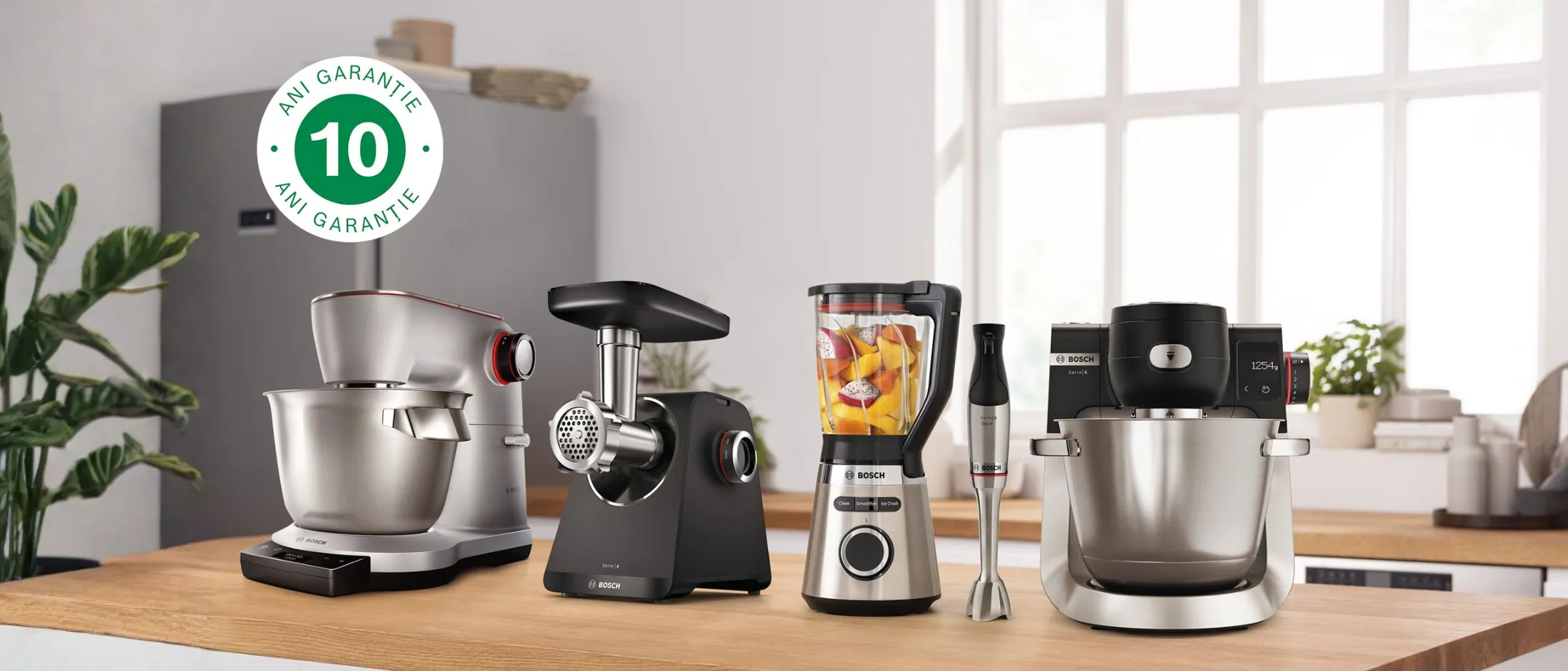 Blat de bucătărie cu cinci aparate de bucătărie Bosch, printre care un mixer de bucătărie, o mașină de tocat carne, un blender, un mixer de mână și un robot de bucătărie, într-un decor modern de bucătărie