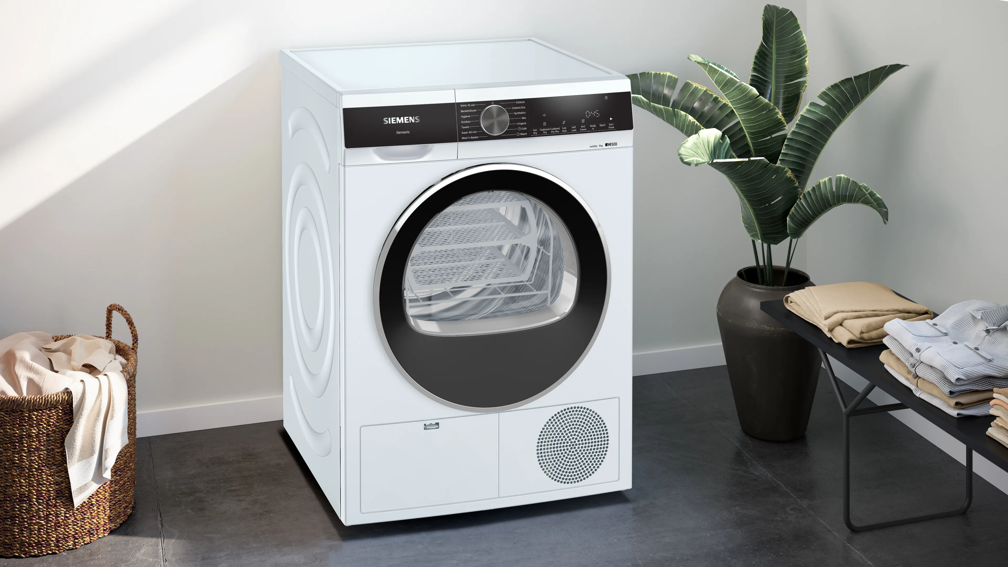 White front-loading clothes dryer on a concrete pedestal against a gray wall with a blue light-patterned backdrop.