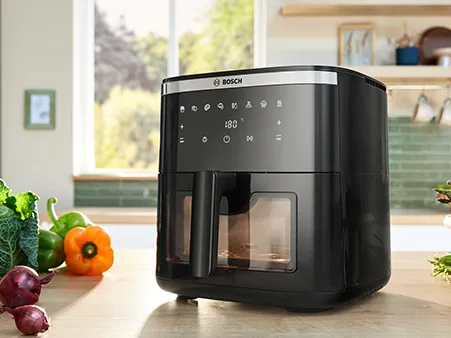 A Bosch Air Fryer Series 6 is positioned on a bright kitchen counter, viewed from the front, showcasing its modern design.