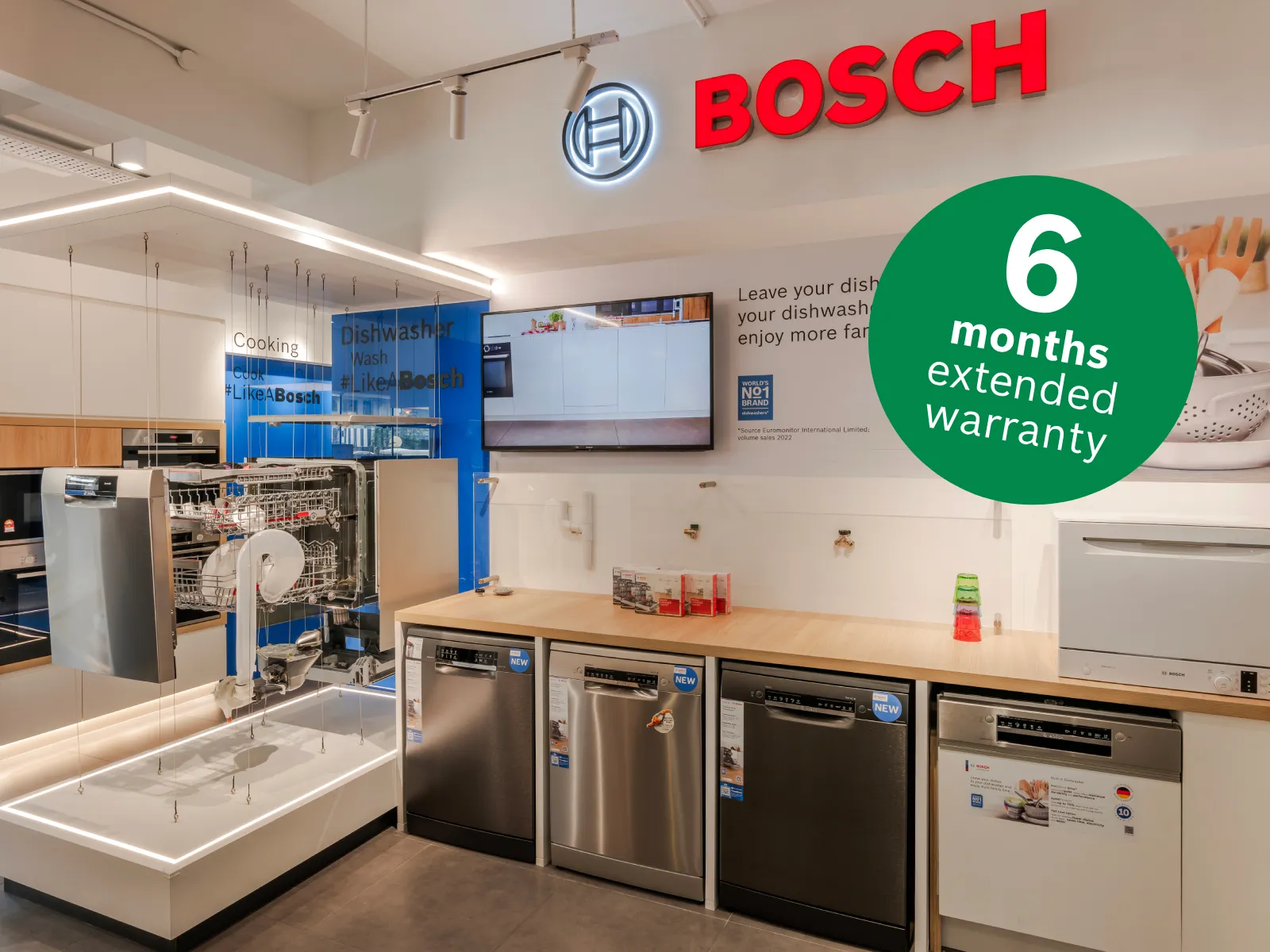 Bosch showroom dishwasher display featuring built-in and tabletop dishwashers, an exploded hanging display unit, and a green badge overlay reading "Extra 6 months warranty."