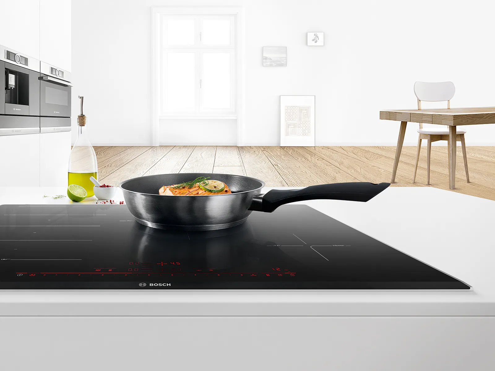 Cocina moderna con placa de inducción, sartén con alimentos y decoración minimalista.