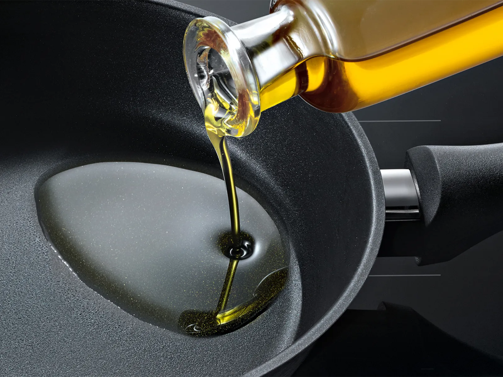Vertiendo aceite de cocina dorado en una sartén negra sobre un fondo oscuro.