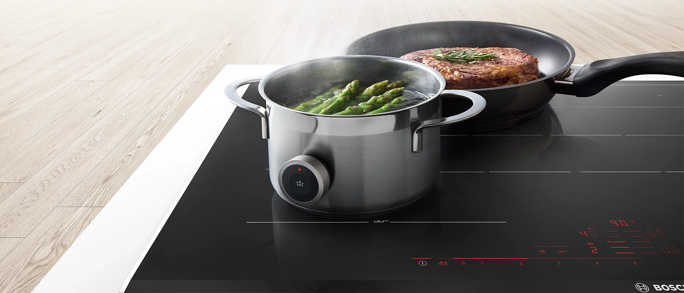 Ollas en la encimera de inducción, plato de espárragos y carne, electrodoméstico de cocina moderno.
