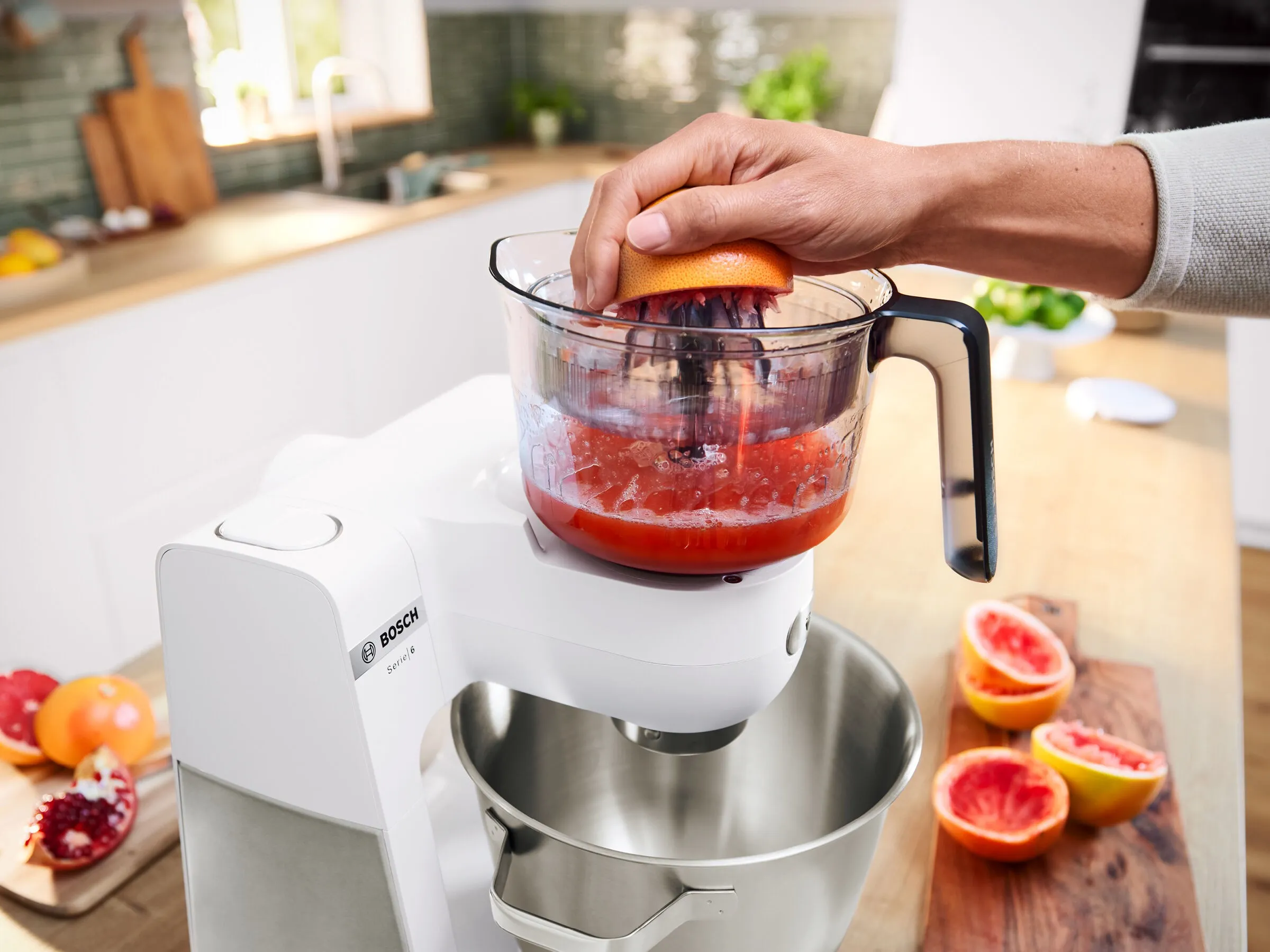The Bosch citrus press VitaStyle with glass jug standing on a kitchen worktop.
