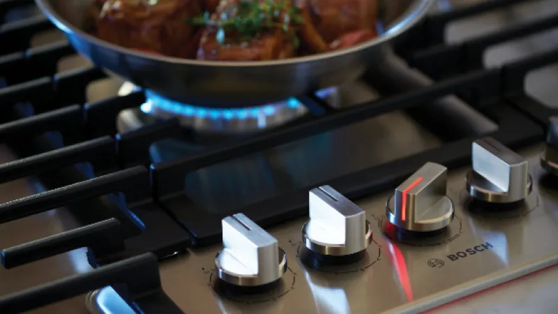 Close-up of Bosch gas stove control knobs on a stainless steel surface, showcasing modern kitchen design and functionality.