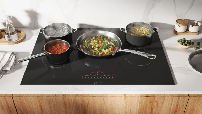 Close-up of a Bosch induction cooktop featuring a sleek black surface with red digital controls and timer functions.