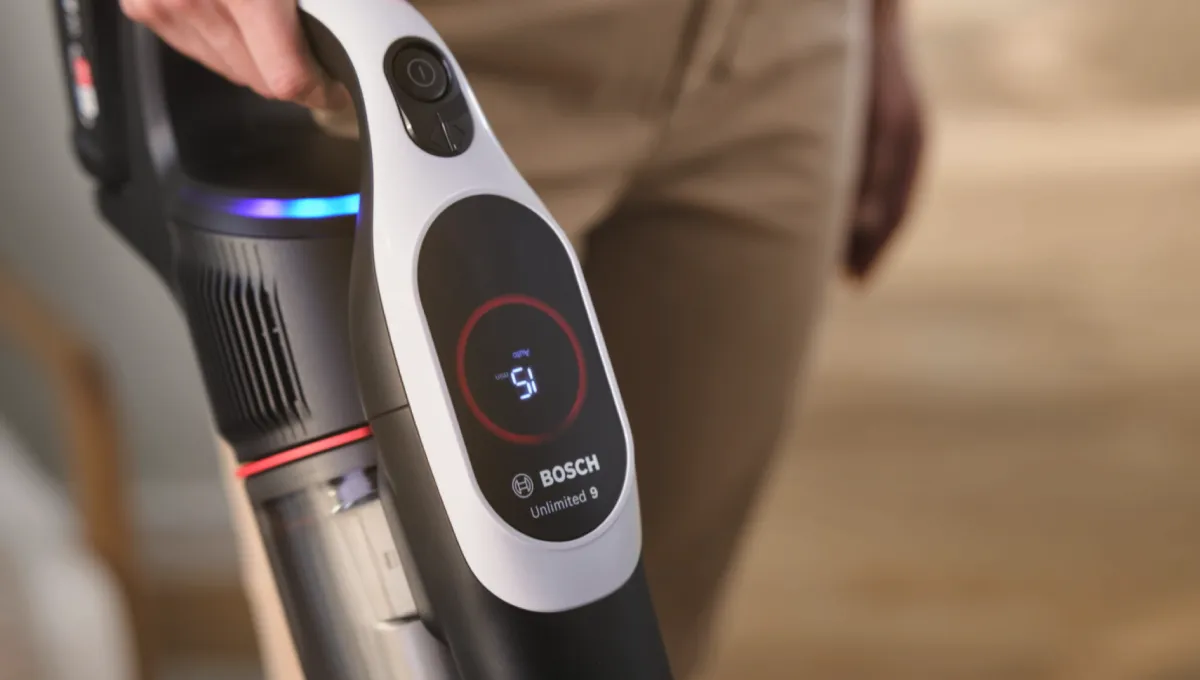 Nahaufnahme einer Hand, die einen kabellosen Bosch Staubsauger hält, mit einer Digitalanzeige, die Batterie- und Modusanzeigen zeigt.