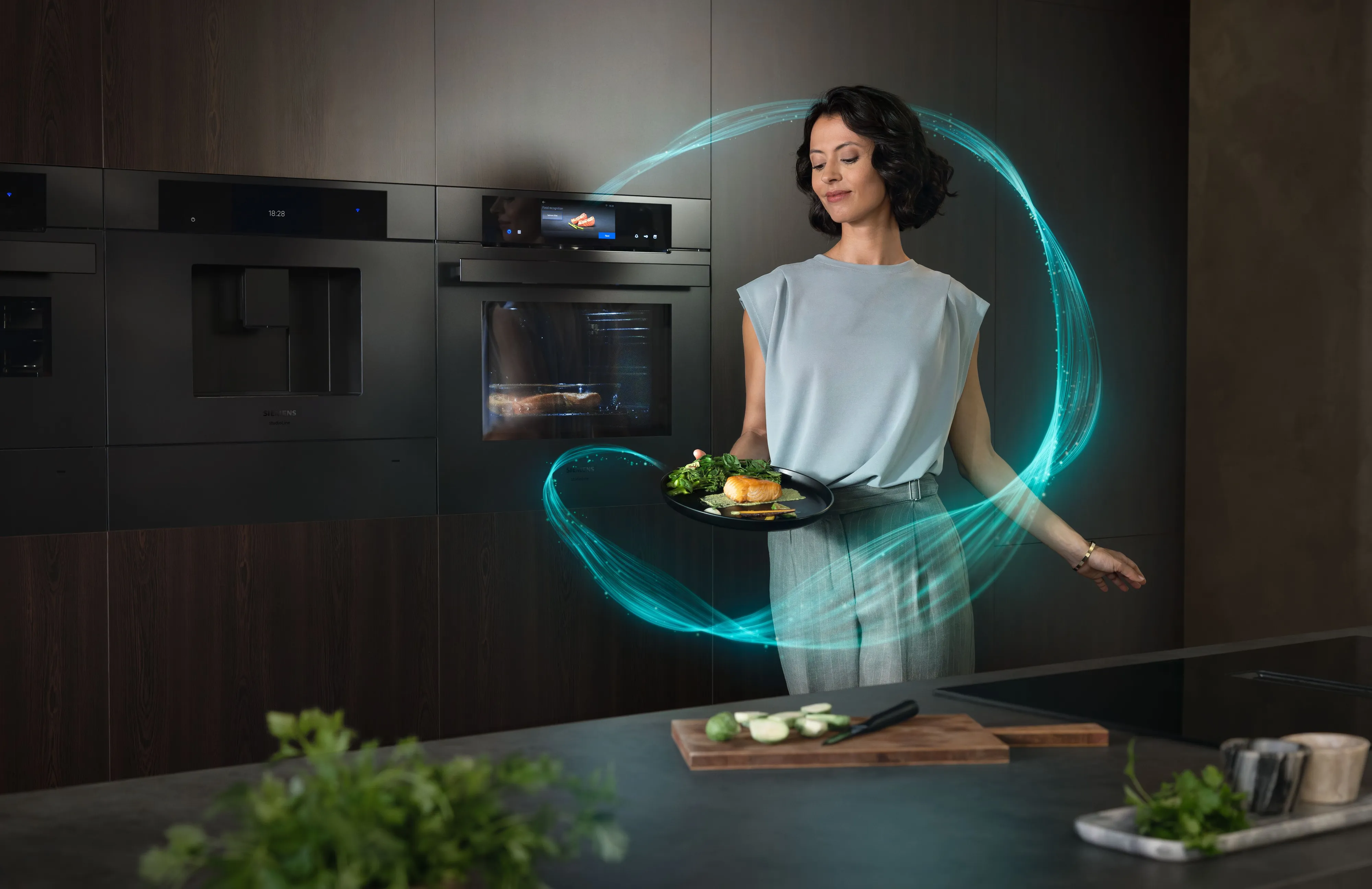 Modern black kitchen island with sleek appliances, a faucet, and potted herbs, showcasing the German Design Award Winner 2026 logo.