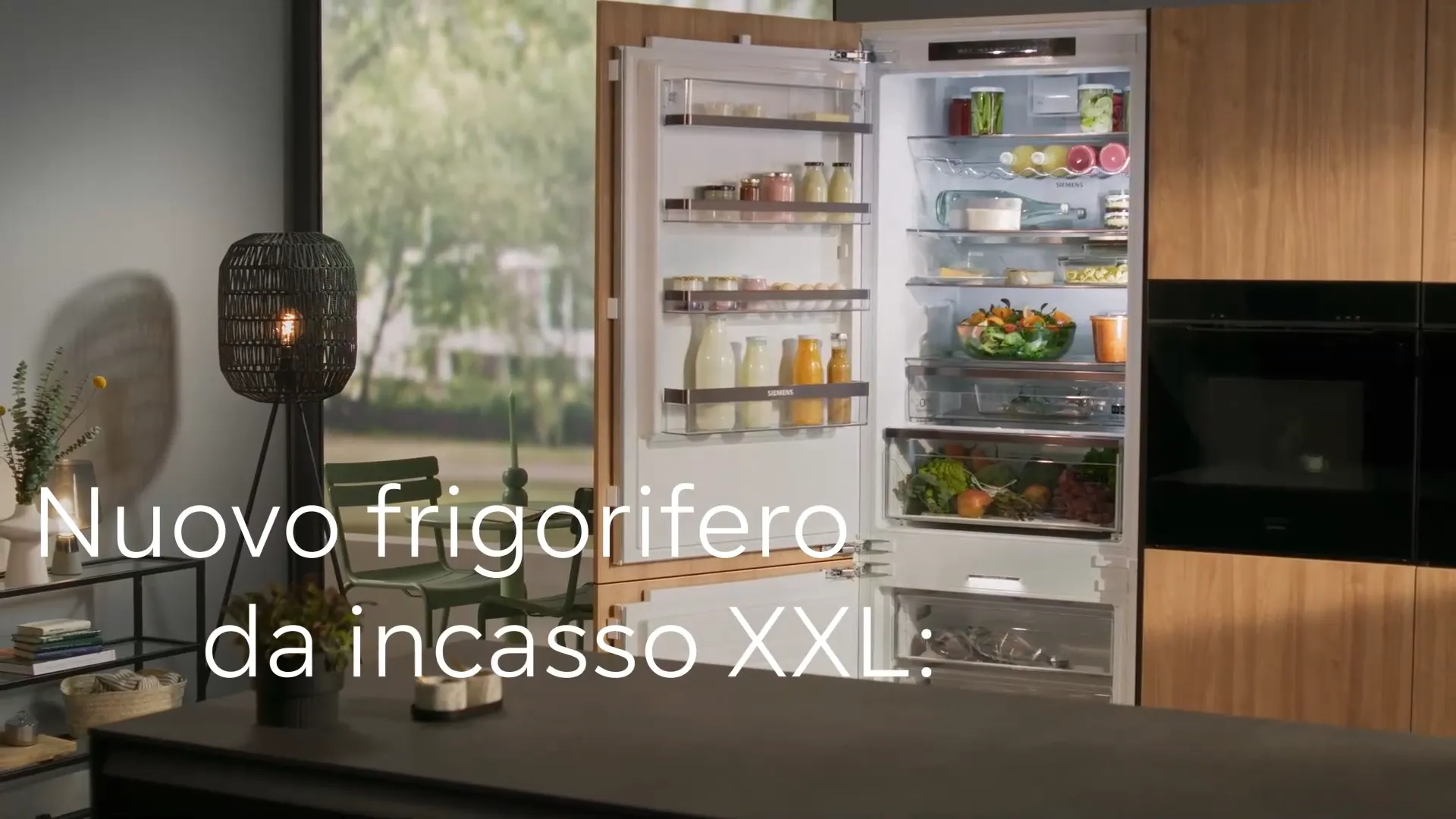 Cucina moderna con frigorifero da incasso XXL aperto accanto a forno a microonde integrato e lampada da tavolo nera.