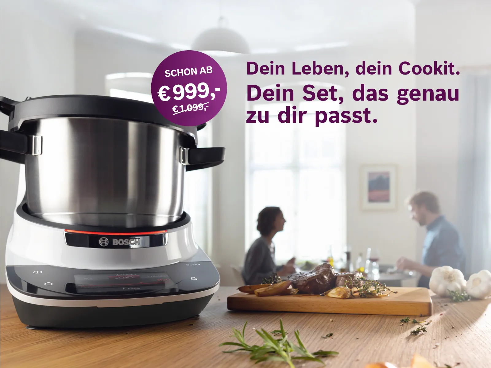 ALT-Text: Bosch Cookit Küchenmaschine mit Kochfunktion auf einer Küchenarbeitsfläche neben einem zubereiteten Gericht. Im Hintergrund sitzen zwei Personen am Esstisch. Text: „Dein Leben, dein Cookit. Dein Set, das genau zu dir passt.“ Schon ab 999 € statt 1.099 €.