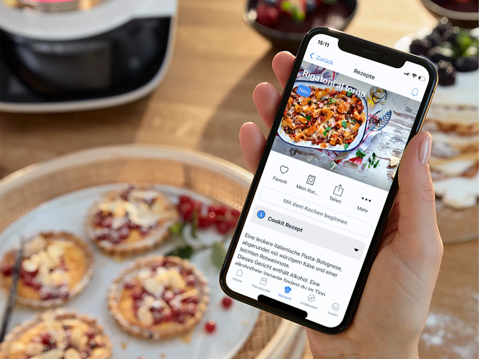Person hält Smartphone mit App zur Essenslieferung, im Hintergrund selbstgemachte Pizzastücke auf einem Holzbrett.