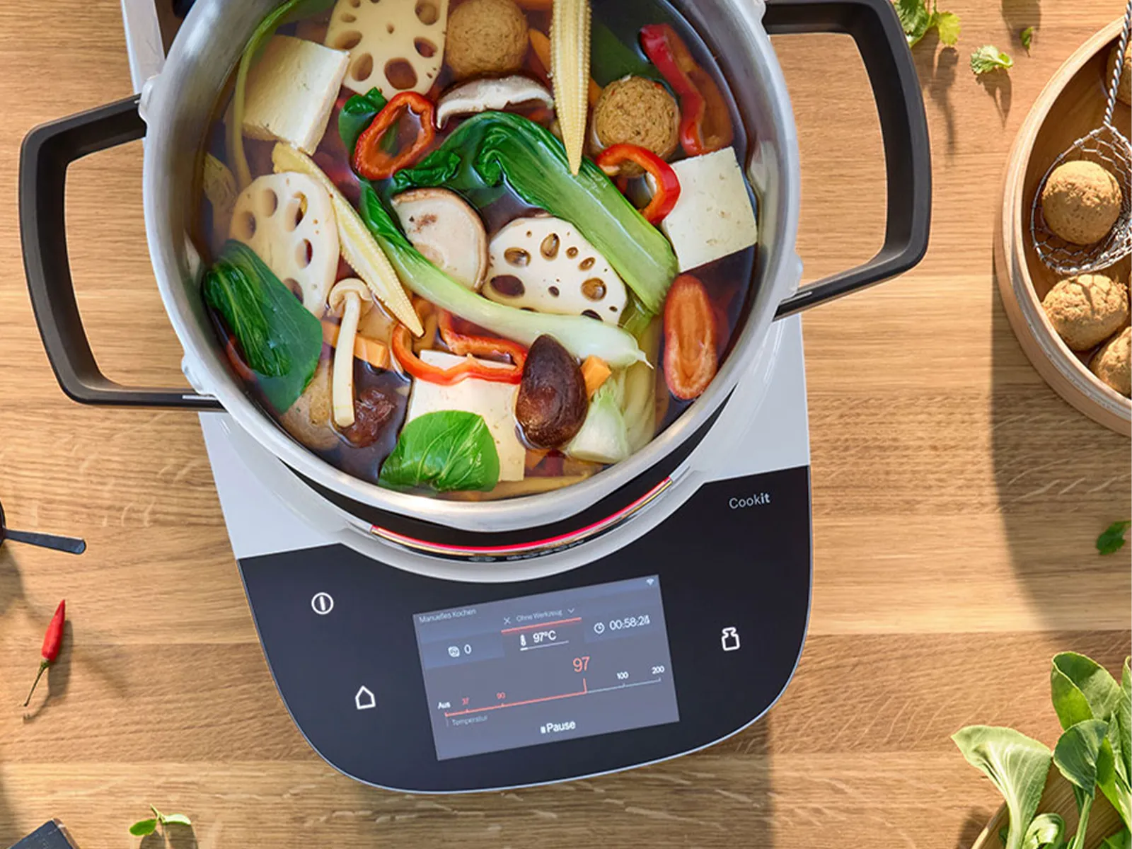 Kochtopf mit Gemüse, Kräutern und Kochutensilien auf Holztisch mit Smartphone.