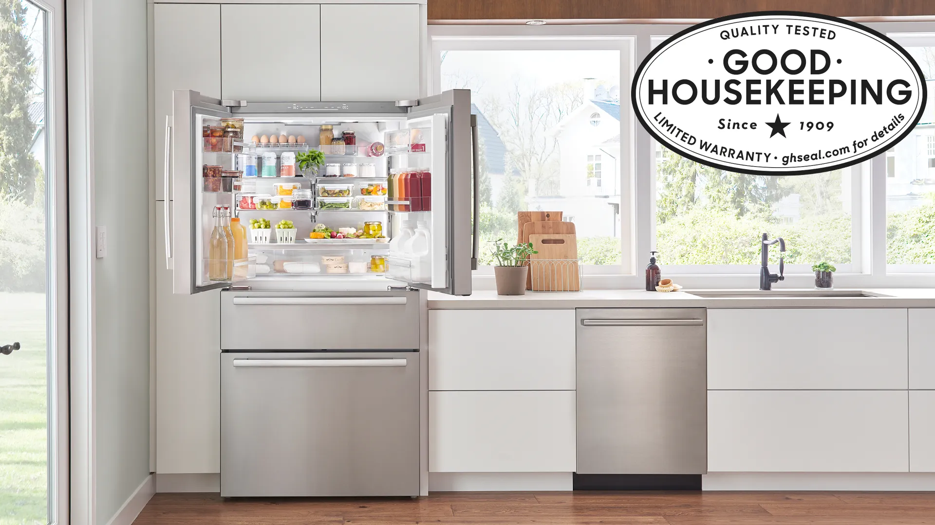 Modern kitchen with Bosch stainless steel fridge and dishwasher, open fridge showing organized contents.