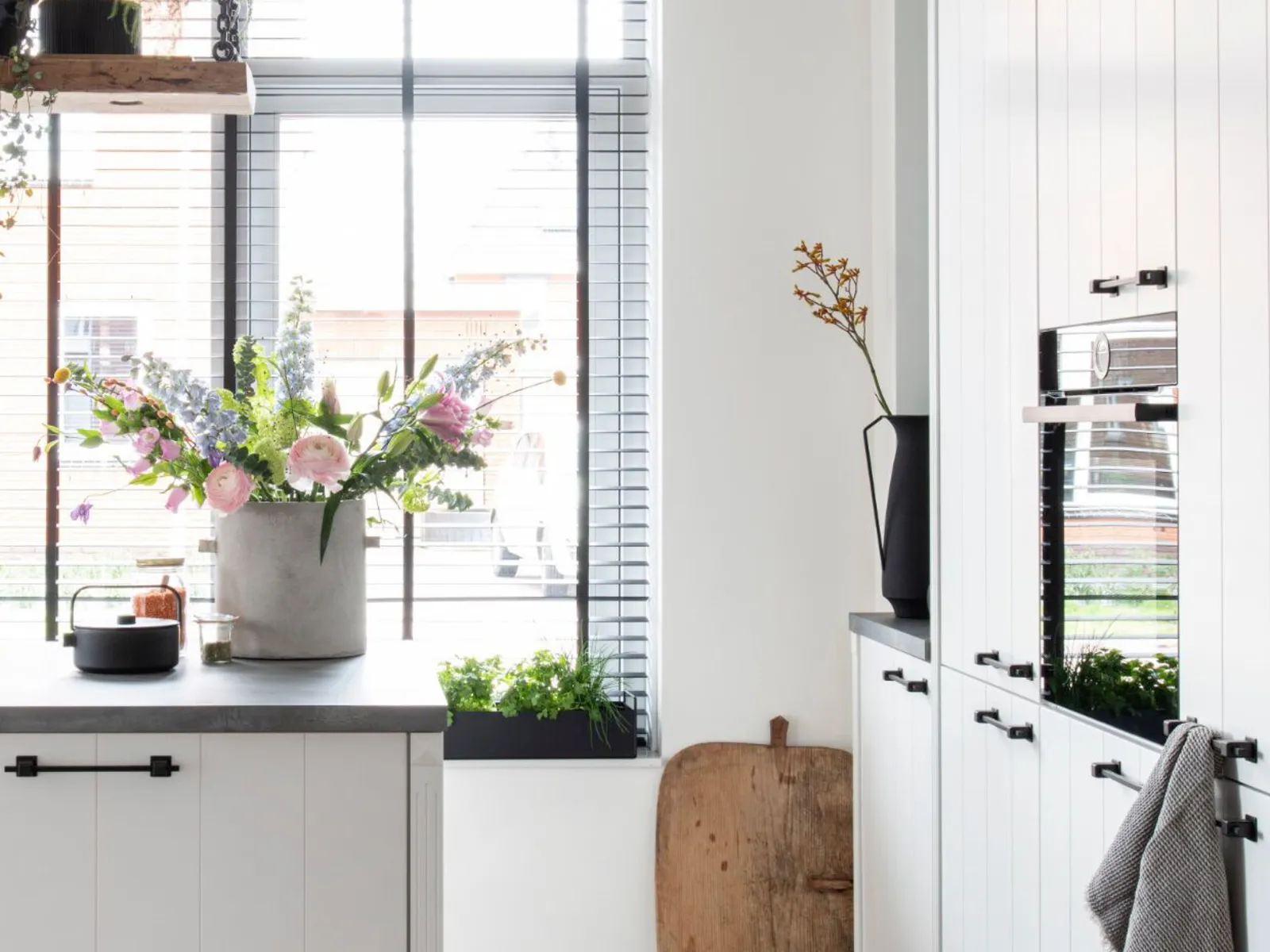 Cuisine lumineuse et moderne avec des plantes en pot, des fleurs et des accents en bois créant une atmosphère chaleureuse et naturelle.