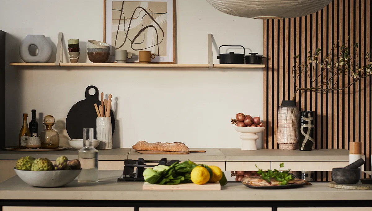 Un bancone da cucina in stile Japandi preparato per la cottura, con pesce fresco, limoni e carciofi accanto a un piano cottura a gas domino NEFF.