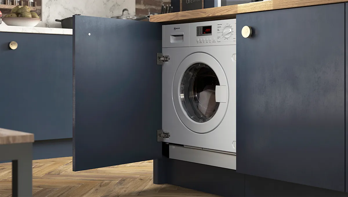 A silver NEFF washing machine revealed behind an open blue cabinet door, seamlessly integrated into the kitchen cabinetry.