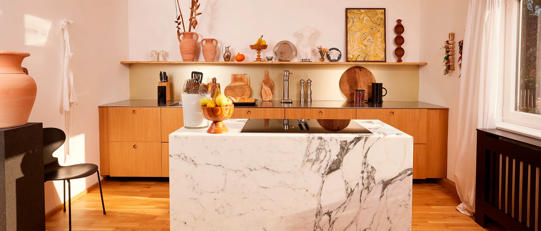 Cozy kitchen with marble countertop, wooden cabinets, and decorative items on shelves.