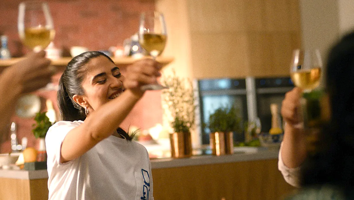 Woman enjoying wine in kitchen with glasses and decor.