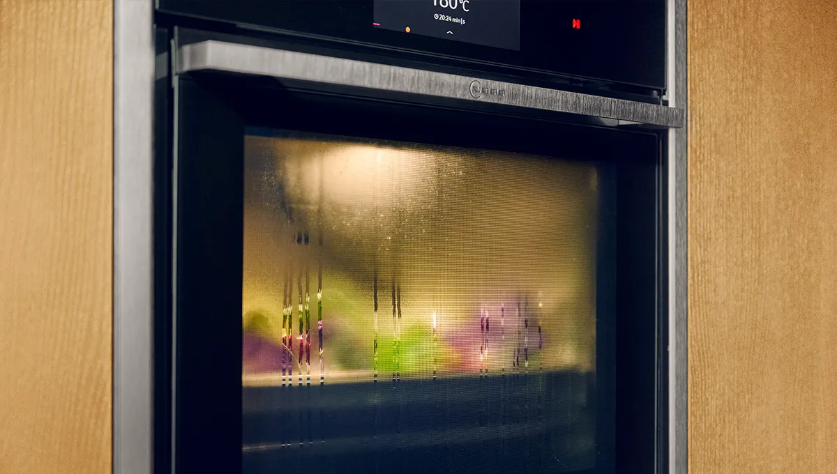 Oven interior with condensation, blurred lights, and temperature display.