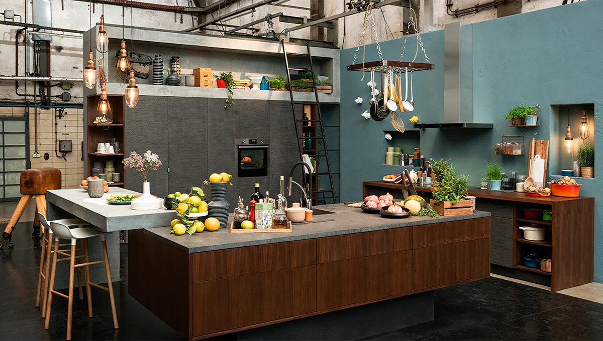 Küche im modernen Industriestil mit Betonarbeitsplatten, Holzschränken, Hängeleuchten und diversen Kochutensilien.