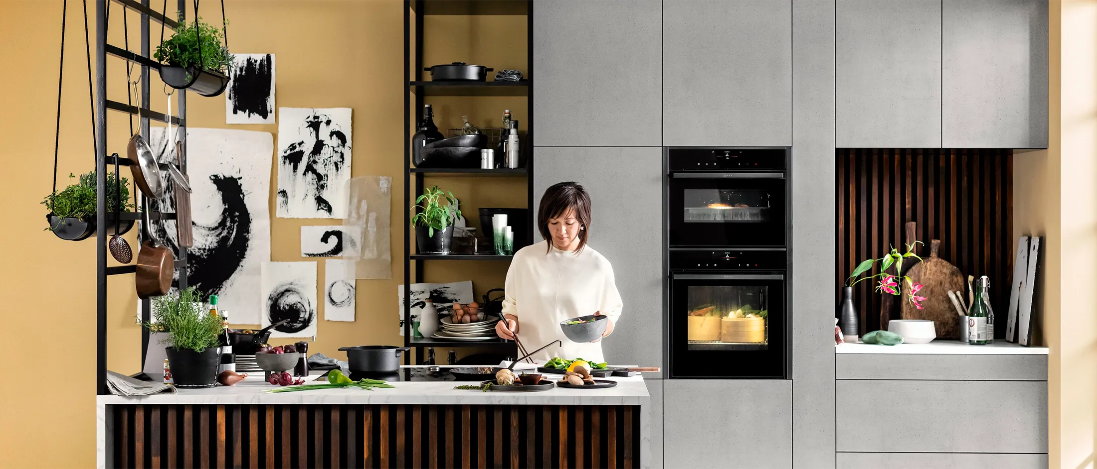 Modern kitchen with woman cooking, shelves, appliances, plants, and decor.