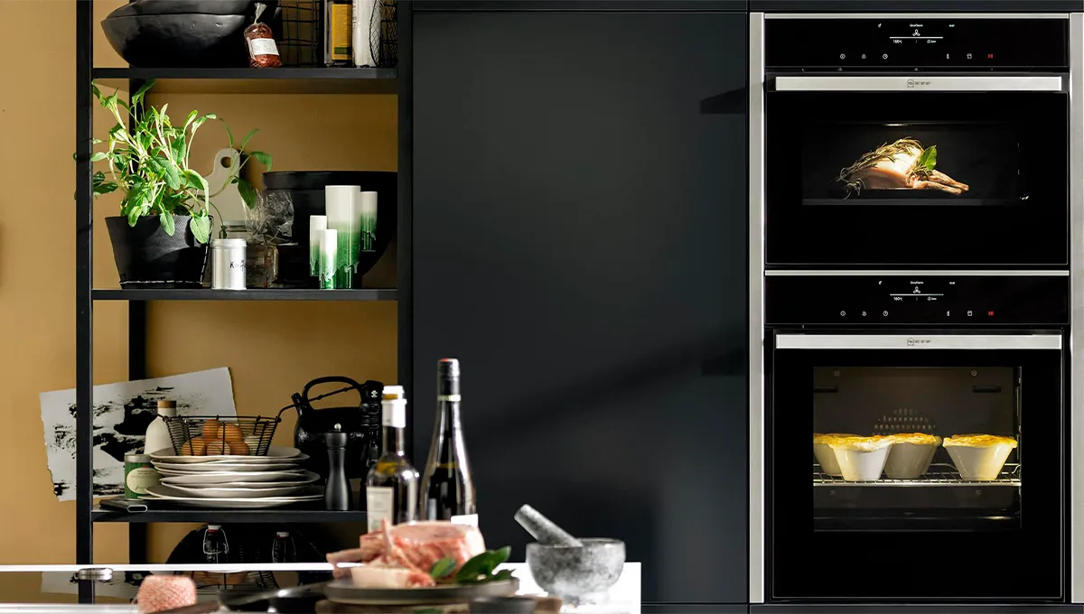 Kitchen countertop with appliances, shelves, and decor items. Dark color scheme with modern design elements.